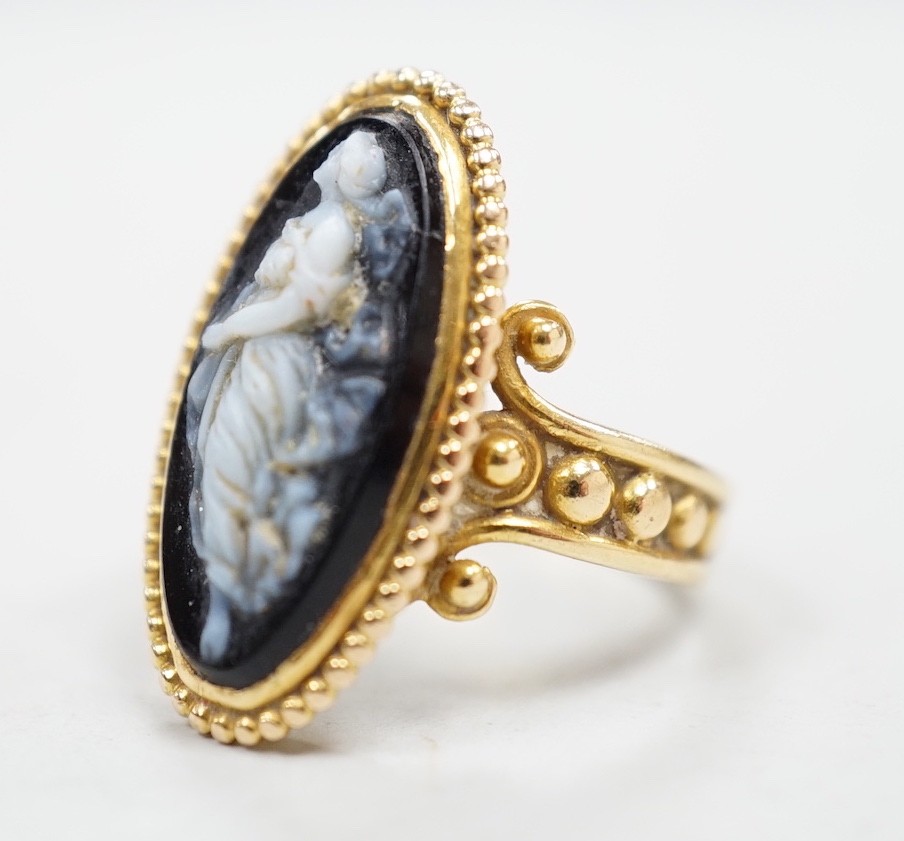 An early 20th century yellow metal and black sardonyx set cameo ring, carved with the figure of a classical lady, size G/H, gross weight 3.3 grams